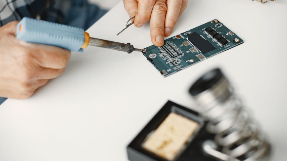 Hands working on electronics at a workbench