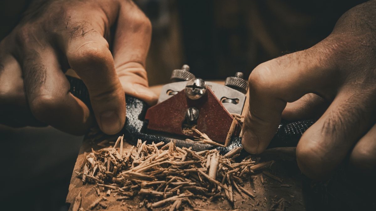 Hands measuring and marking a board on a woodworking bench